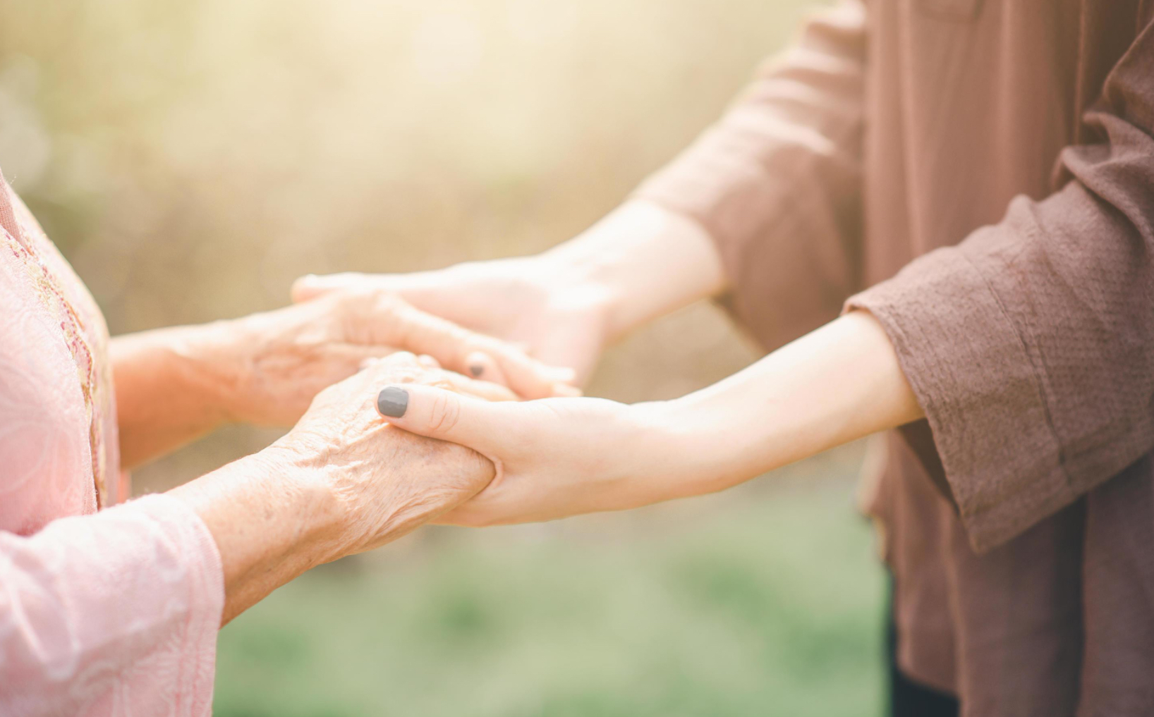 Caregiver and elderly holding hands
